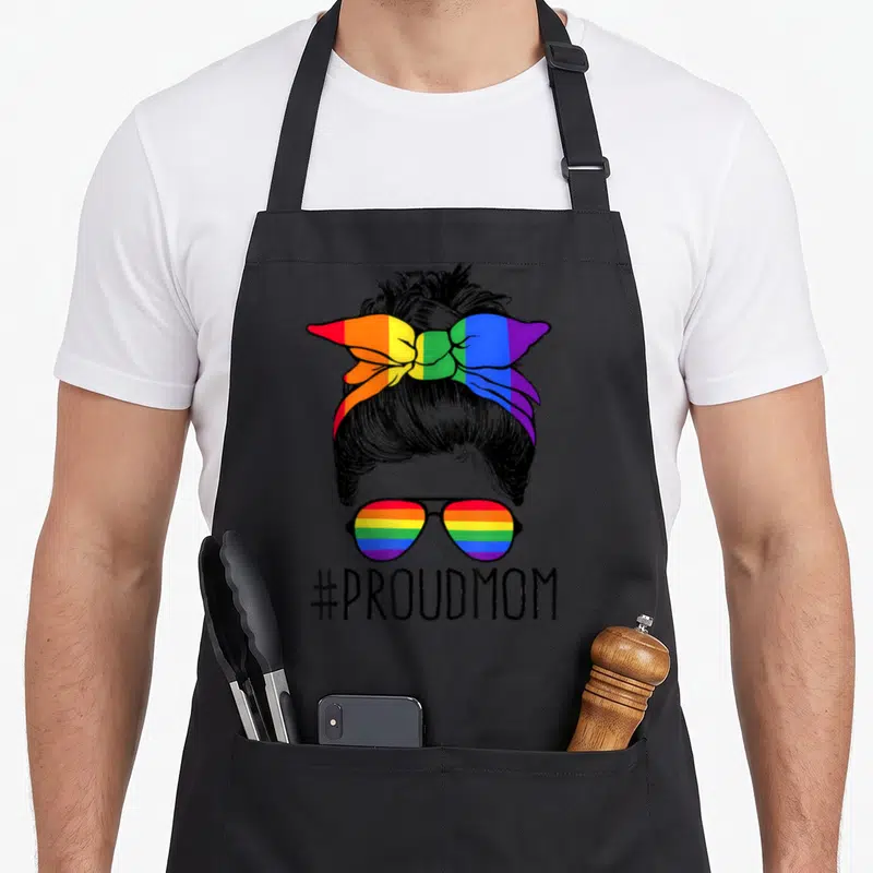 Proud messy aprons - Line art woman bun rainbow headband sunglasses #PROUDMOM — shown on a black cotton canvas apron against a white background
