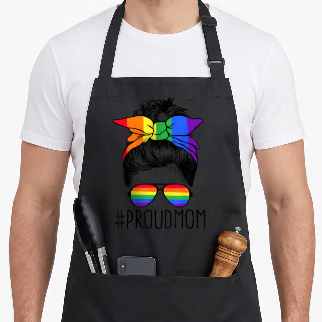 Proud messy aprons - Line art woman bun rainbow headband sunglasses #PROUDMOM — shown on a black cotton canvas apron against a white background