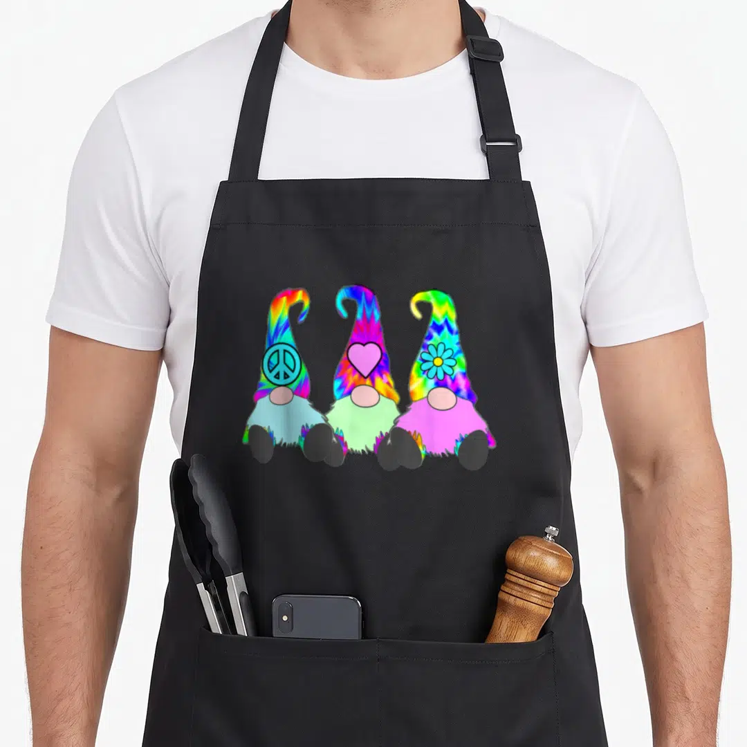 Hat tie-dye apron - Three rainbow-hatted gnomes with peace, heart, and flower symbols — shown on a black cotton canvas apron against a white background