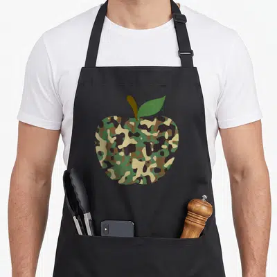 Apple camo apron - Single apple shape filled with green brown tan and black camo pattern with stem and leaf — shown on a black cotton canvas apron against a white background