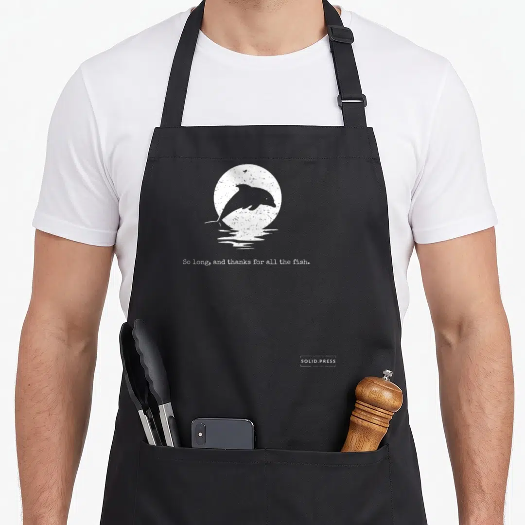 Funny thank fish apron - White distressed dolphin jumping before sun with text So long and thanks for all the fish — shown on a black cotton canvas apron against a white background