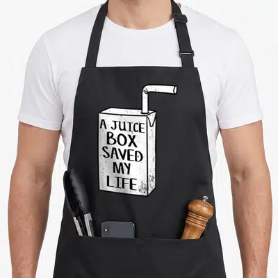Juice box apron - White juice box with straw and A JUICE BOX SAVED MY LIFE text — shown on a black cotton canvas apron against a white background