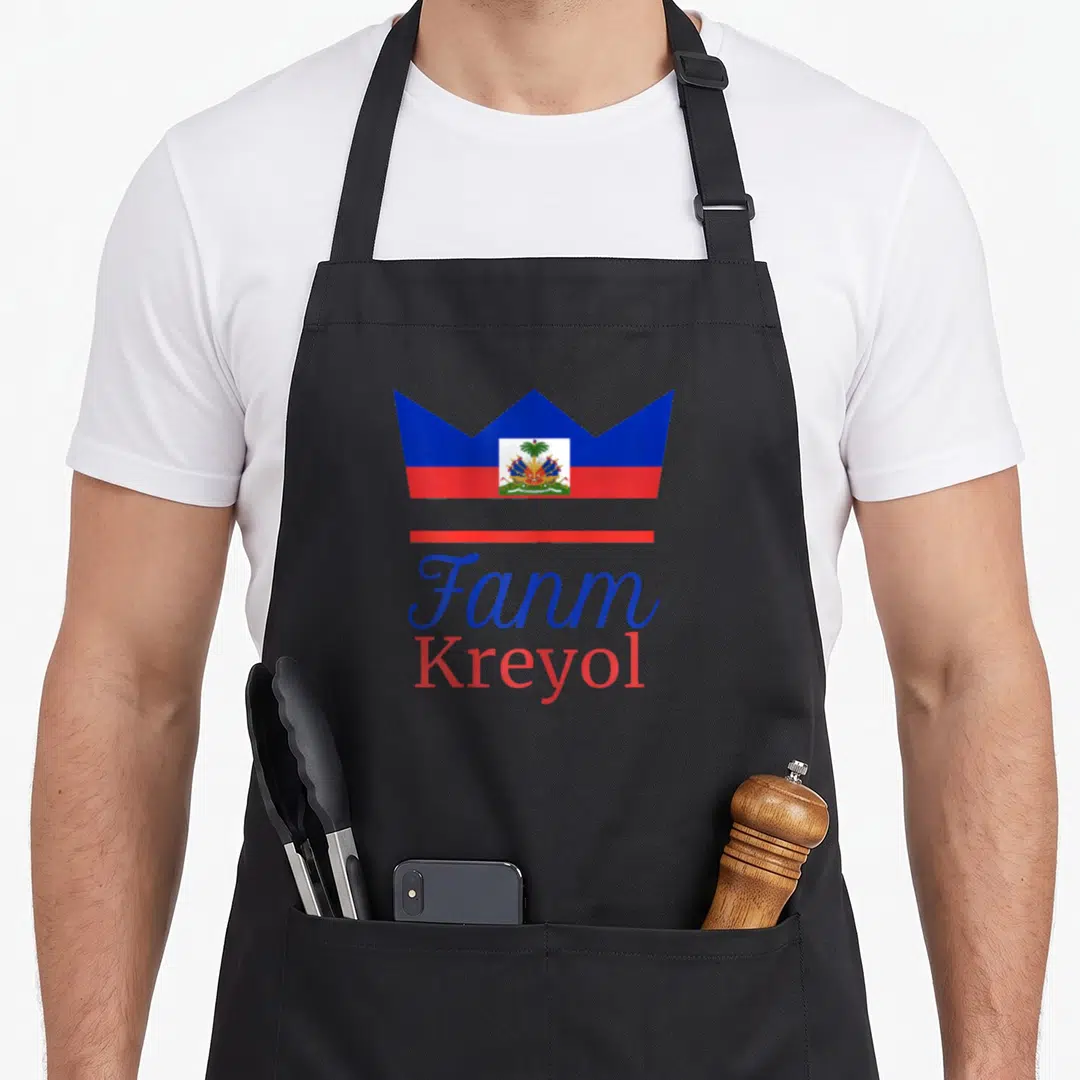 Fanm pride apron - Crown filled with Haitian flag above red line and stacked Fanm Kreyol text in blue and red script — shown on a black cotton canvas apron against a white background