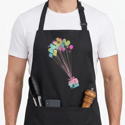 Water balloon apron - Multicolored watercolor house lifted by a cluster of balloons with thin strings on black fabric — shown on a black cotton canvas apron against a white background