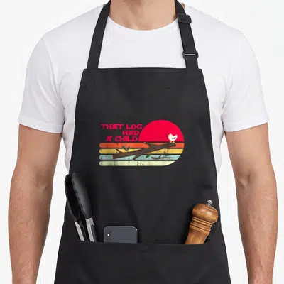 Seagull meme apron - Retro sunset with red orange yellow stripes, brown log, perched white bird, and red stacked text — shown on a black cotton canvas apron against a white background