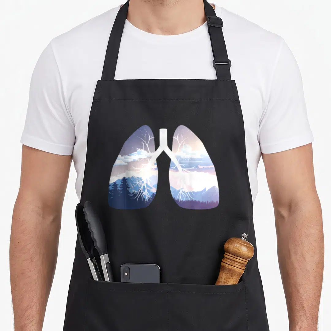 Breathe clean apron - Lung silhouette containing blue purple mountains forests and white tree branch bronchial tubes — shown on a black cotton canvas apron against a white background