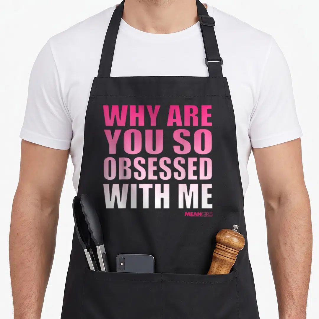 Obsessed mean girls apron - Stacked pink to white gradient text reading WHY ARE YOU SO OBSESSED WITH ME — shown on a black cotton canvas apron against a white background