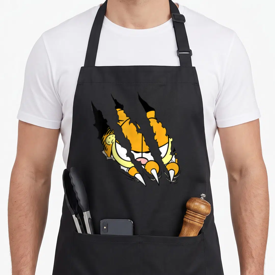 Claw general apron - Three diagonal claw tears revealing tiger face and fur in yellow black white cartoon style — shown on a black cotton canvas apron against a white background
