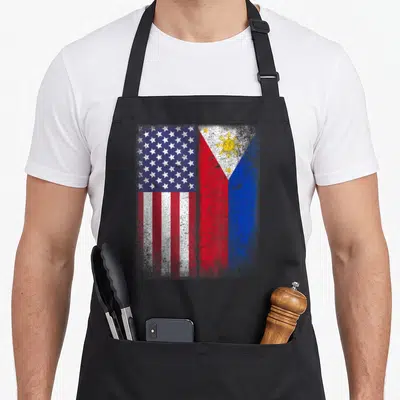 Filipino american flag apron - Two national flags side-by-side in red white blue and yellow with distressed texture — shown on a black cotton canvas apron against a white background