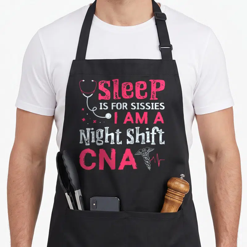 Nurse nursing aprons - Distressed pink and white text reading sleep is for sissies I am a night shift CNA — shown on a black cotton canvas apron against a white background
