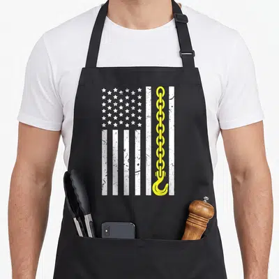Thin truck apron - Distressed white flag with yellow chain and hook replacing one stripe — shown on a black cotton canvas apron against a white background