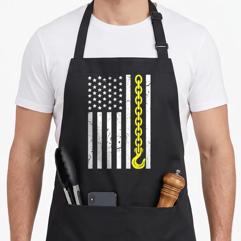 Thin truck apron - Distressed white flag with yellow chain and hook replacing one stripe — shown on a black cotton canvas apron against a white background