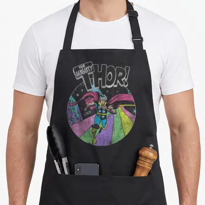 Mighty distressed apron - Retro Thor running on rainbow path with THE MIGHTY THOR! text in circular frame — shown on a black cotton canvas apron against a white background