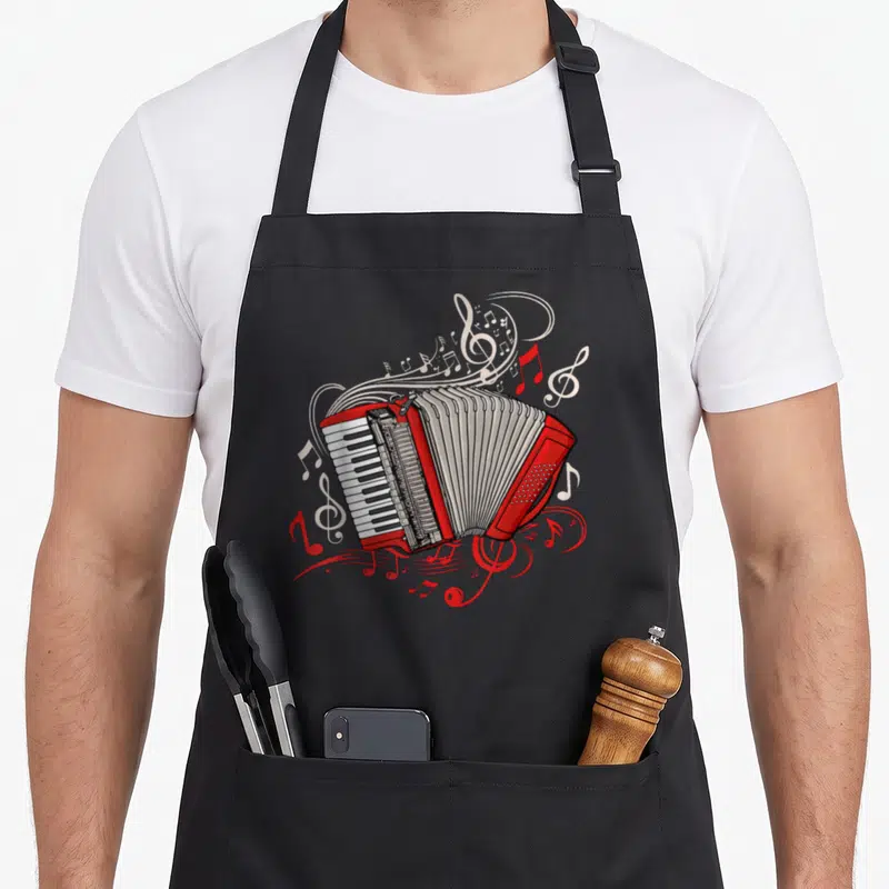 Player accordion apron - Red cartoon accordion surrounded by swirling white and red musical notes and staff lines — shown on a black cotton canvas apron against a white background