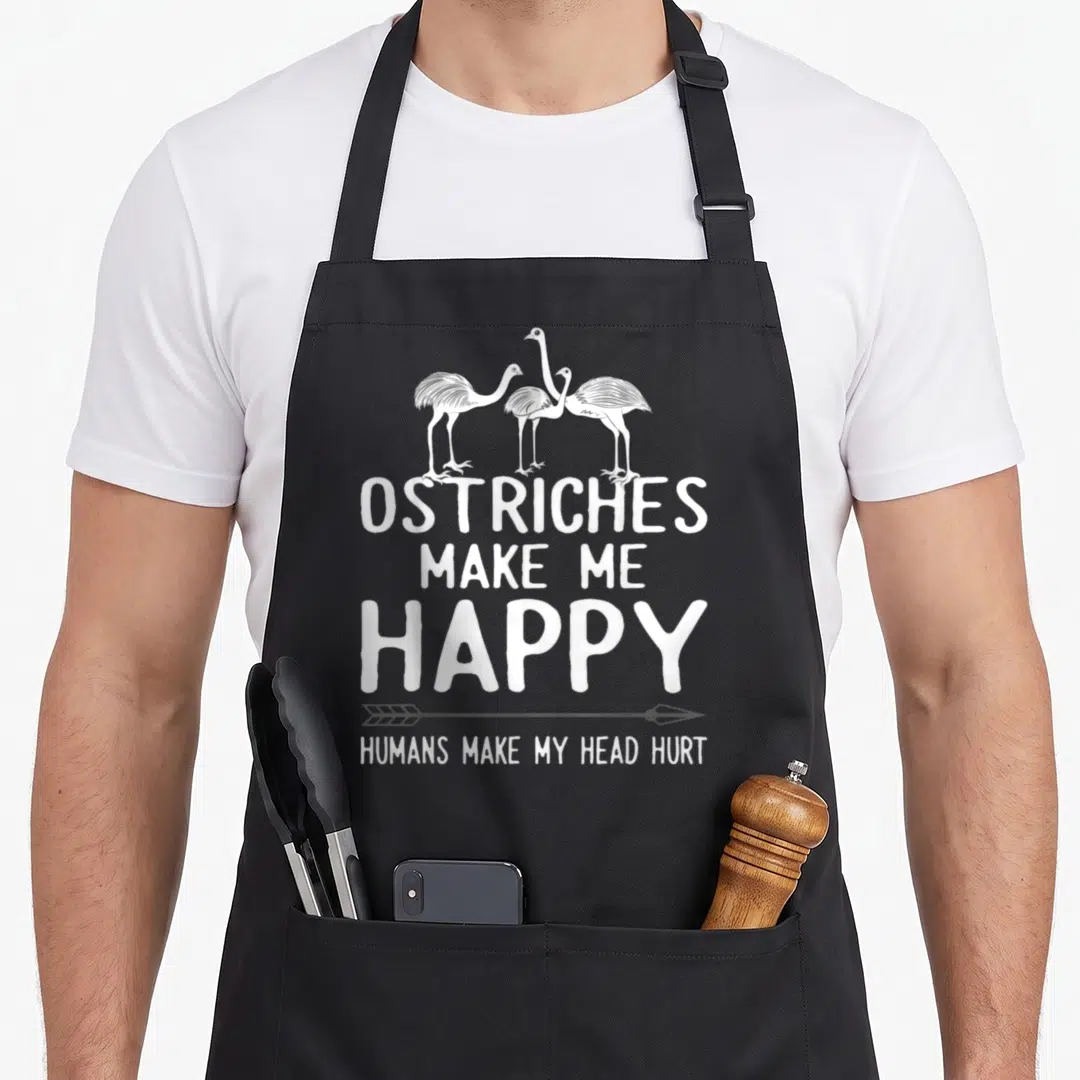 Cute animal i love my ostrich apron - Three white ostriches above text reading OSTRICHES MAKE ME HAPPY HUMANS MAKE MY — shown on a black cotton canvas apron against a white background