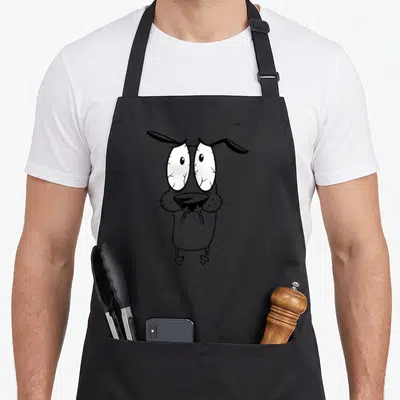 Cowardly dog apron - Centered cartoon dog with wide eyes in grey, black, and white — shown on a black cotton canvas apron against a white background