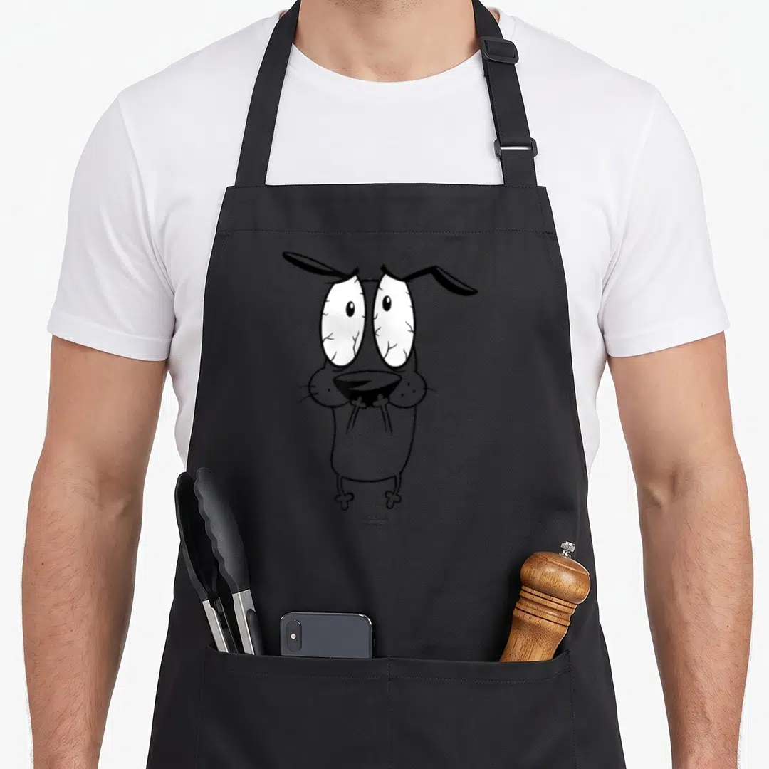 Cowardly dog apron - Centered cartoon dog with wide eyes in grey, black, and white — shown on a black cotton canvas apron against a white background