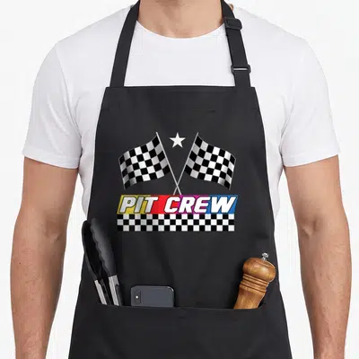Stock car apron - Two crossed checkered flags above PIT CREW text on yellow red pink and blue banner — shown on a black cotton canvas apron against a white background