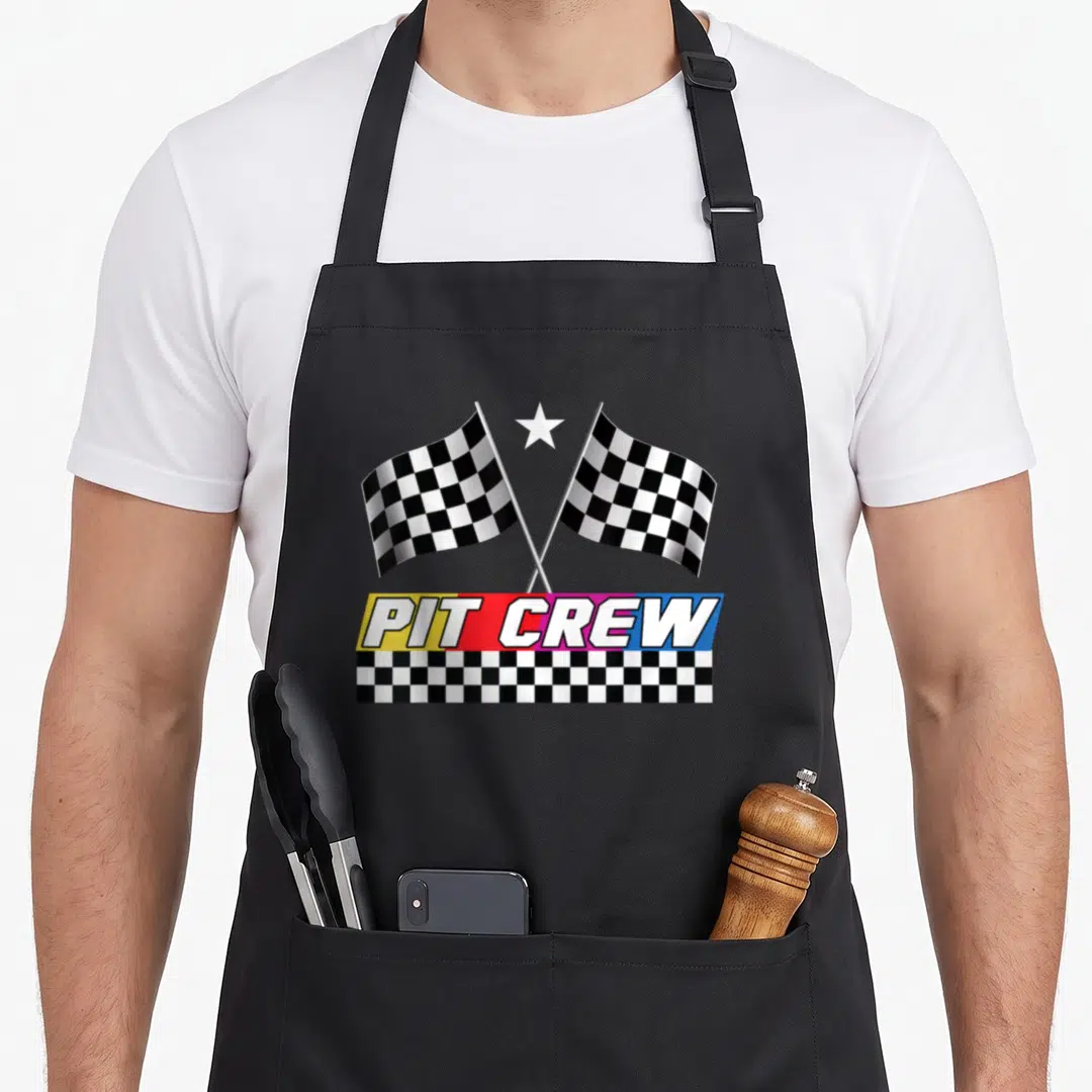 Stock car apron - Two crossed checkered flags above PIT CREW text on yellow red pink and blue banner — shown on a black cotton canvas apron against a white background