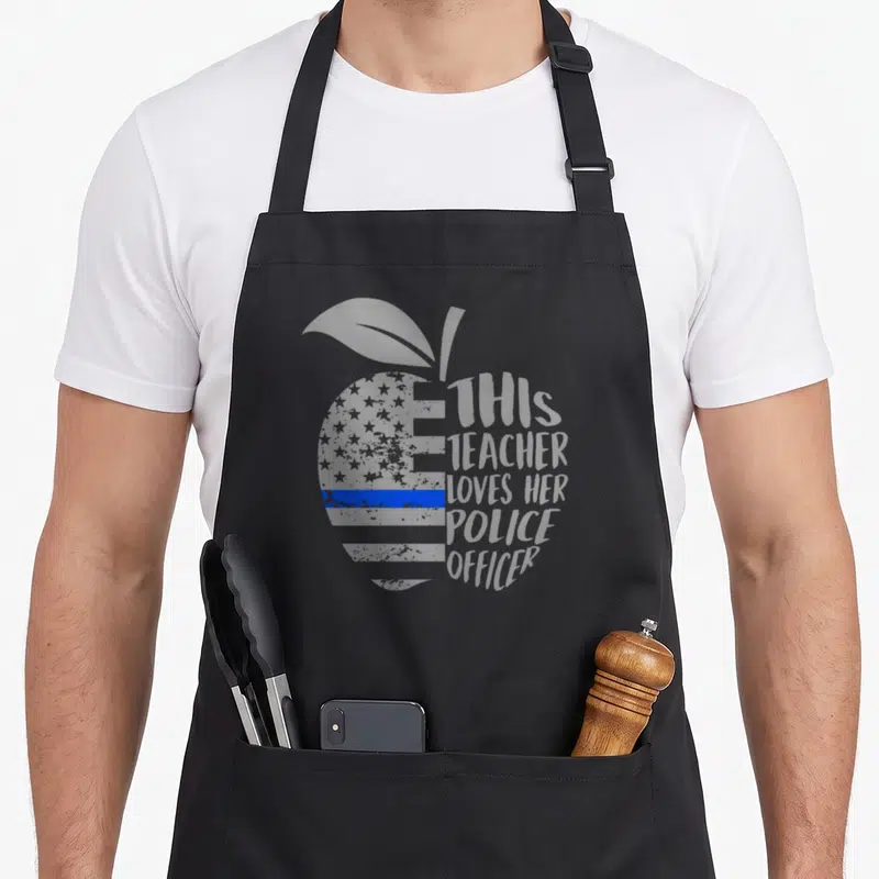 Officer best teacher apron - Grey apple shape with stars blue line and text THIS TEACHER LOVES HER POLICE OFFICER — shown on a black cotton canvas apron against a white background