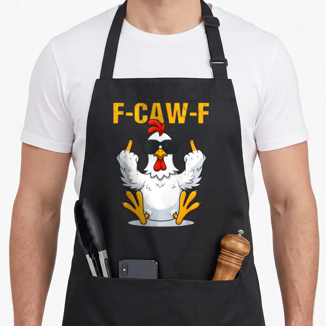 Kaw rooster apron - F-CAW-F text above a winged cartoon chicken wearing sunglasses — shown on a black cotton canvas apron against a white background