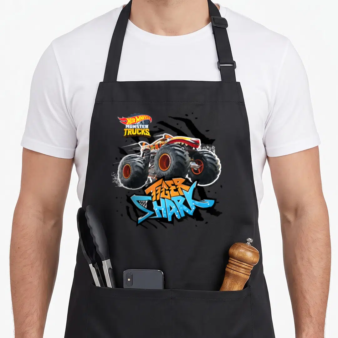 Funny tiger shark apron - Monster truck illustration with HOT WHEELS logo and Tiger Shark text in orange and blue — shown on a black cotton canvas apron against a white background
