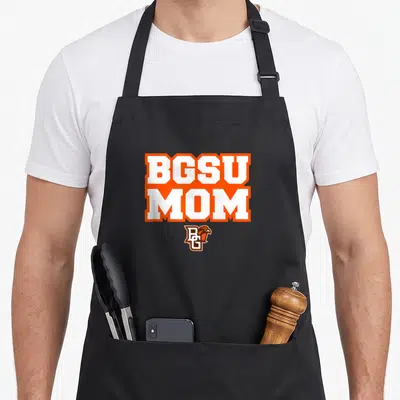Funny bowling falcon apron - BGSU MOM text in white with orange borders above a small BGSU falcon logo — shown on a black cotton canvas apron against a white background