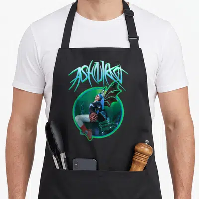 Ashnikko dragon apron - Arched ASHNIKKO text above winged woman in glowing circle with blue, green, red, and black — shown on a black cotton canvas apron against a white background