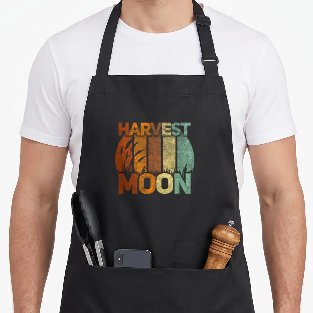 Harvest fall aprons - Retro circular moon with vertical orange yellow green stripes and wheat stalks overlaid — shown on a black cotton canvas apron against a white background