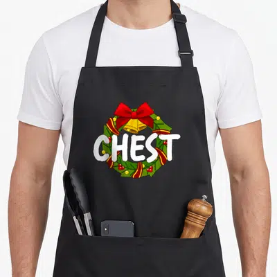 Cool nut couples christmas aprons - CHEST text over green red gold cartoon Christmas wreath with bells and bow — shown on a black cotton canvas apron against a white background