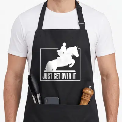 Hunter english apron - White horse and rider jumping silhouette with text JUST GET OVER IT inside a frame — shown on a black cotton canvas apron against a white background