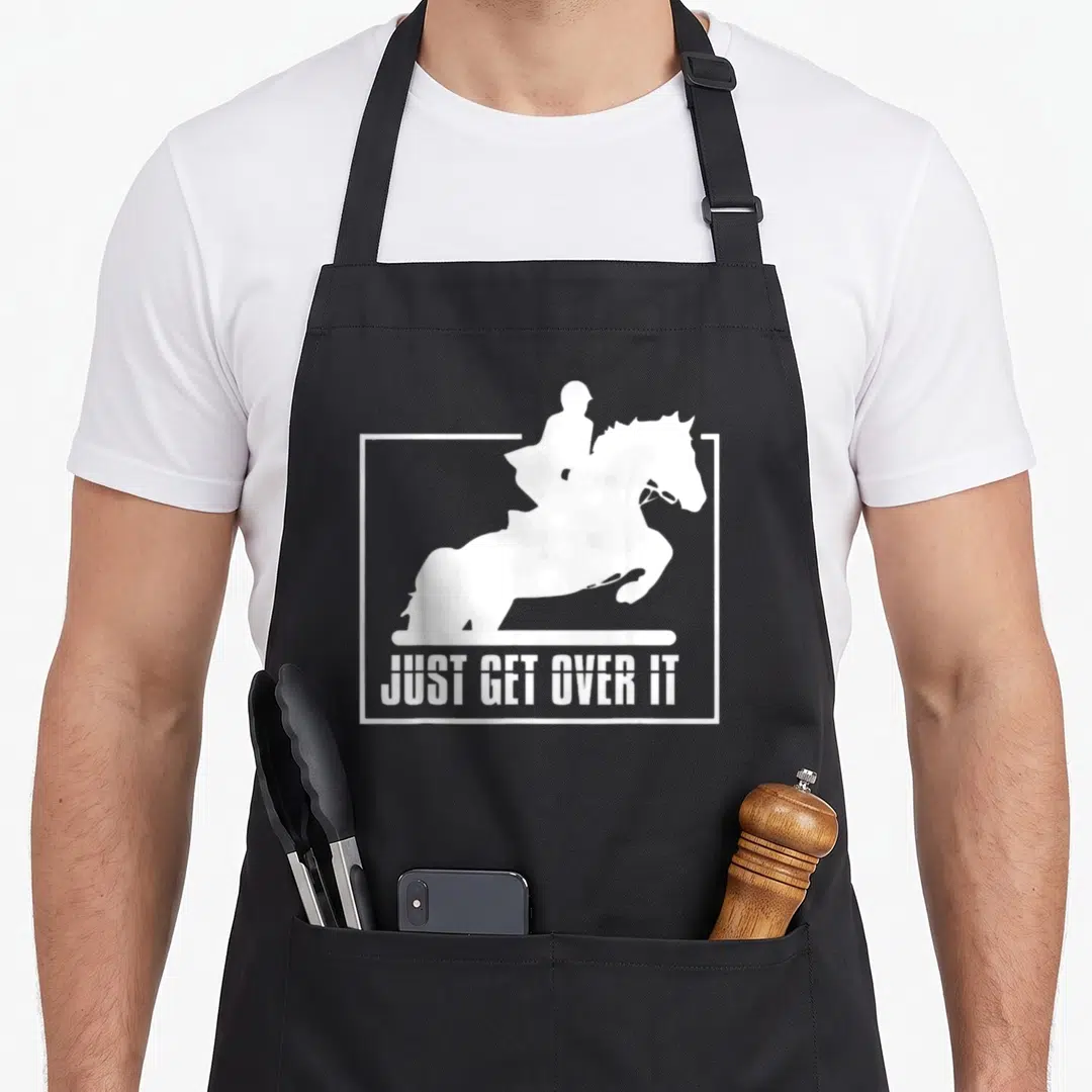 Hunter english apron - White horse and rider jumping silhouette with text JUST GET OVER IT inside a frame — shown on a black cotton canvas apron against a white background