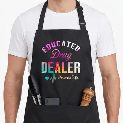 Educated drug nurse apron - Stacked colorful text reading Educated Drug Dealer with a teal heartbeat line — shown on a black cotton canvas apron against a white background