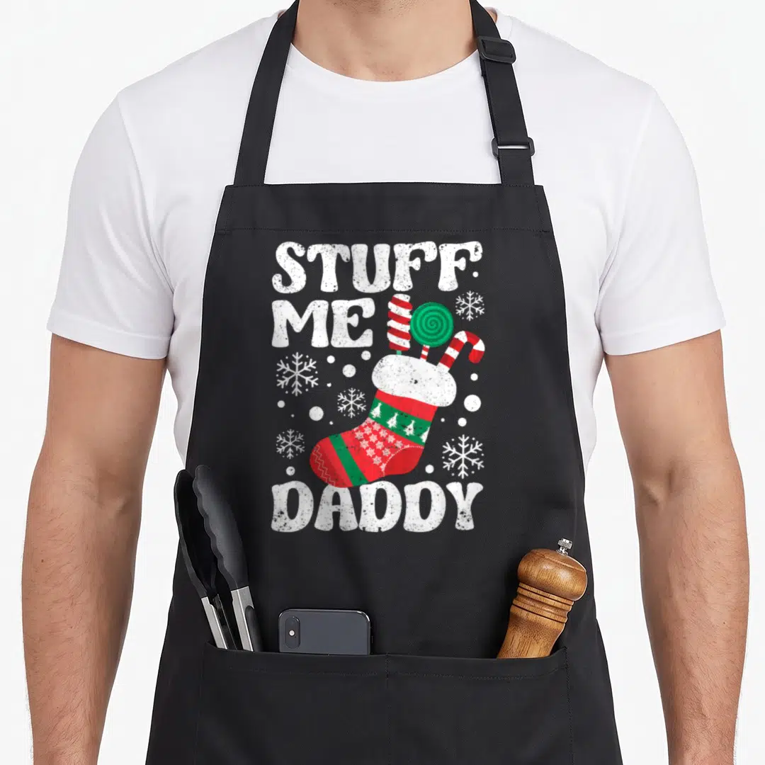 Daddy womens christmas aprons - STUFF ME DADDY text with red green stocking and candy — shown on a black cotton canvas apron against a white background