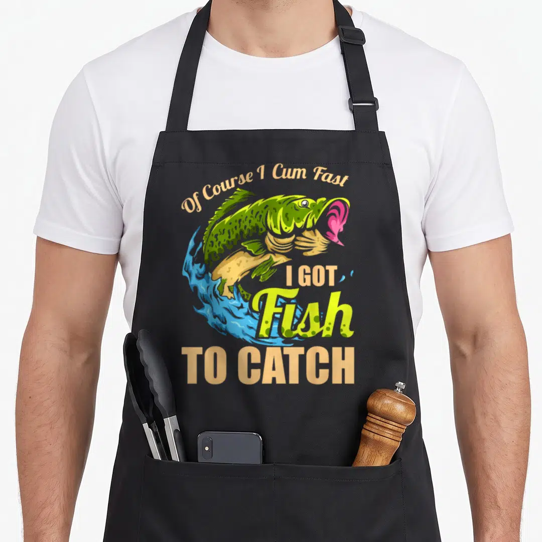 Course fish apron - Green fish leaping from blue water with peach text reading Of Course I Cum Fast I Got Fish To Catch — shown on a black cotton canvas apron against a white background