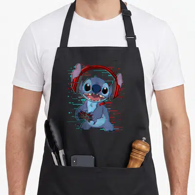 Gamer novelty apron - Cartoon Stitch wearing red headphones and holding a controller with blue and red digital glitch — shown on a black cotton canvas apron against a white background