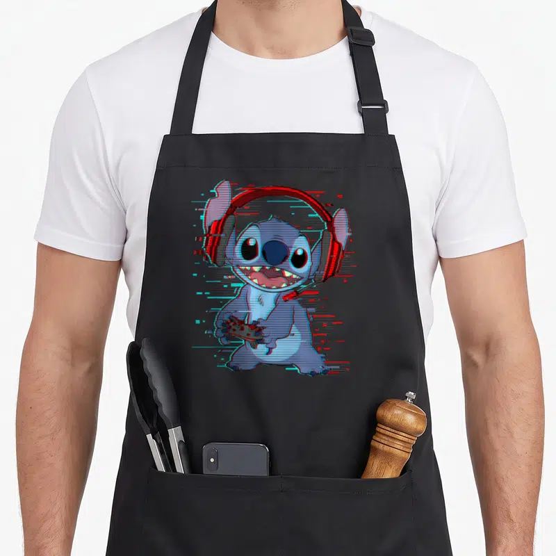 Gamer novelty apron - Cartoon Stitch wearing red headphones and holding a controller with blue and red digital glitch — shown on a black cotton canvas apron against a white background