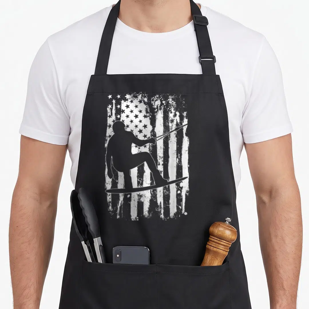 Funny wakeboard wakeboarding apron - Grey wakeboarder silhouette holding rope in front of distressed white and grey — shown on a black cotton canvas apron against a white background