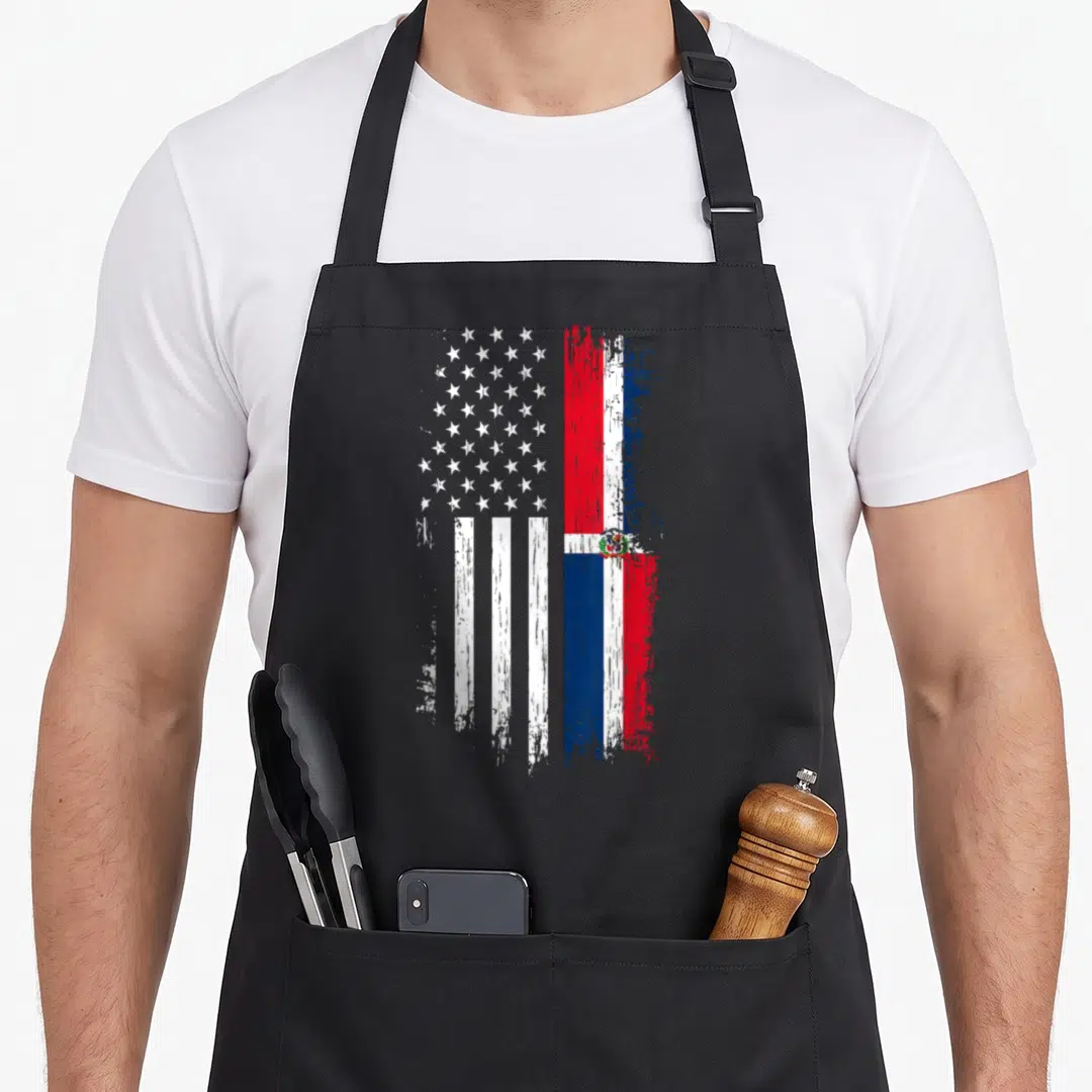Dominica american flag apron - Two merged flags in distressed red white and blue paint splatter style — shown on a black cotton canvas apron against a white background