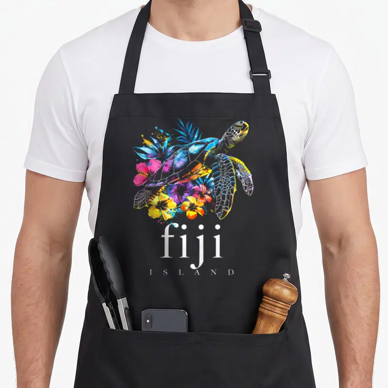 Turtle fiji apron - Sea turtle with blue yellow pink white floral watercolor and fiji I S L A N D text — shown on a black cotton canvas apron against a white background