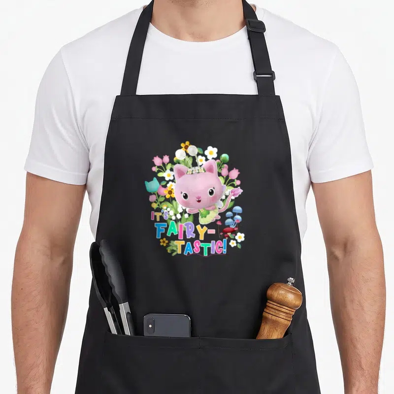 Gabby kitty aprons - Pink fairy cat surrounded by flowers and mushrooms with IT'S FAIRY-TASTIC! text — shown on a black cotton canvas apron against a white background