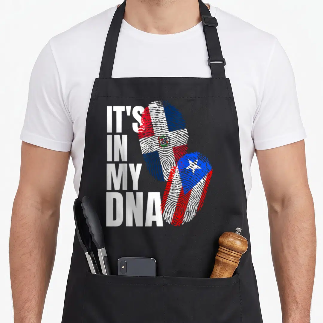Dominican heritage aprons - IT'S IN MY DNA text next to two fingerprints filled with Dominican and Puerto Rican flags — shown on a black cotton canvas apron against a white background
