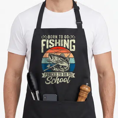 Forced school bass fishing aprons - Retro sun graphic with bass fish, rod, and text Born To Go Fishing Forced To Go — shown on a black cotton canvas apron against a white background
