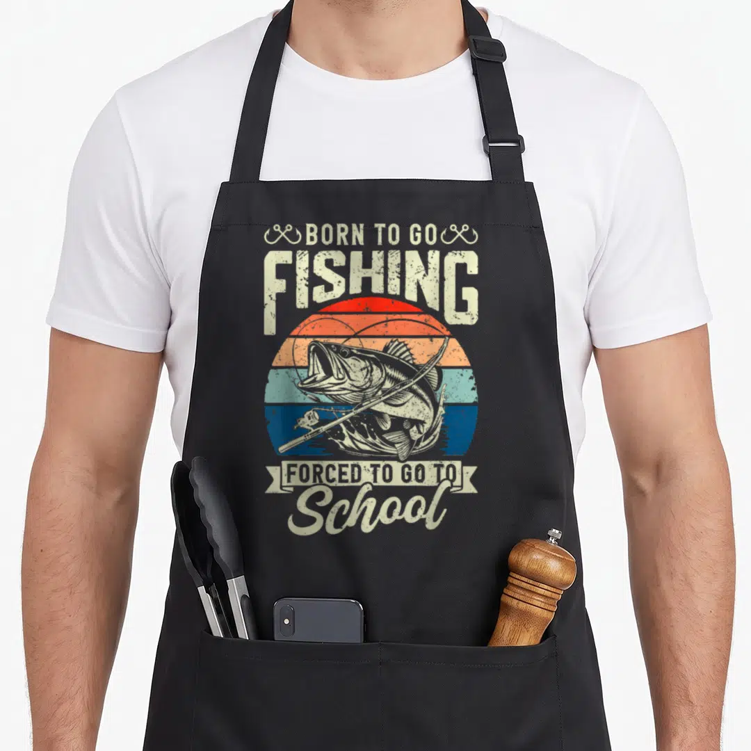 Forced school bass fishing aprons - Retro sun graphic with bass fish, rod, and text Born To Go Fishing Forced To Go — shown on a black cotton canvas apron against a white background