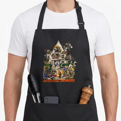 Fraternity animal apron - Cartoon house scene with ANIMAL HOUSE text in red and yellow arch — shown on a black cotton canvas apron against a white background
