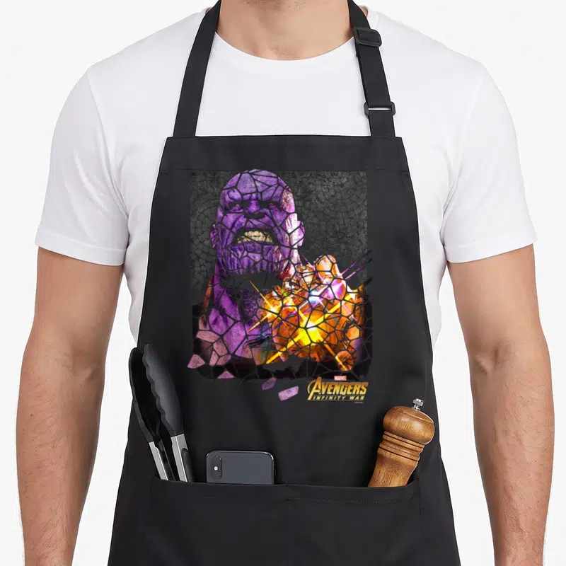 Infinity stained apron - Shattered purple and gold Thanos mosaic with Avengers Infinity War logo — shown on a black cotton canvas apron against a white background