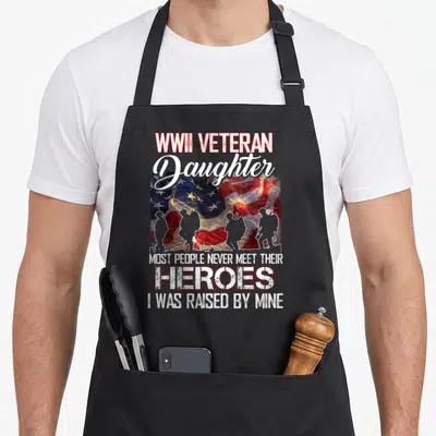 Veteran people meet apron - Waving USA flag with four soldier silhouettes and fireworks behind text reading WWII — shown on a black cotton canvas apron against a white background