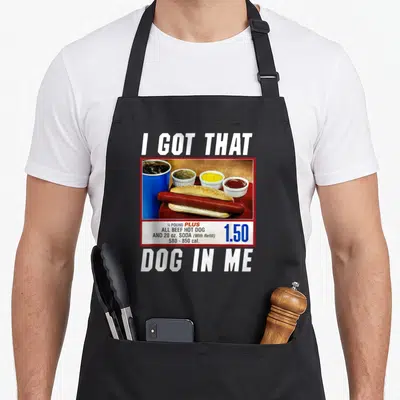 Vintage hot dog apron - I Got That Dog In Me text above hot dog meal photo with 1.50 price tag — shown on a black cotton canvas apron against a white background