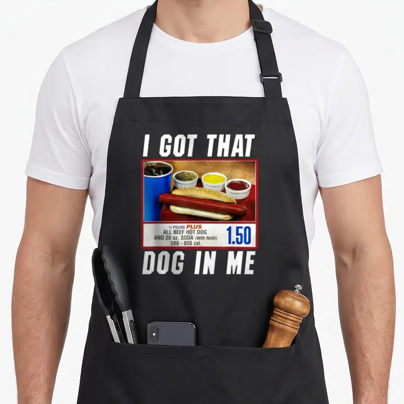 Vintage hot dog apron - I Got That Dog In Me text above hot dog meal photo with 1.50 price tag — shown on a black cotton canvas apron against a white background