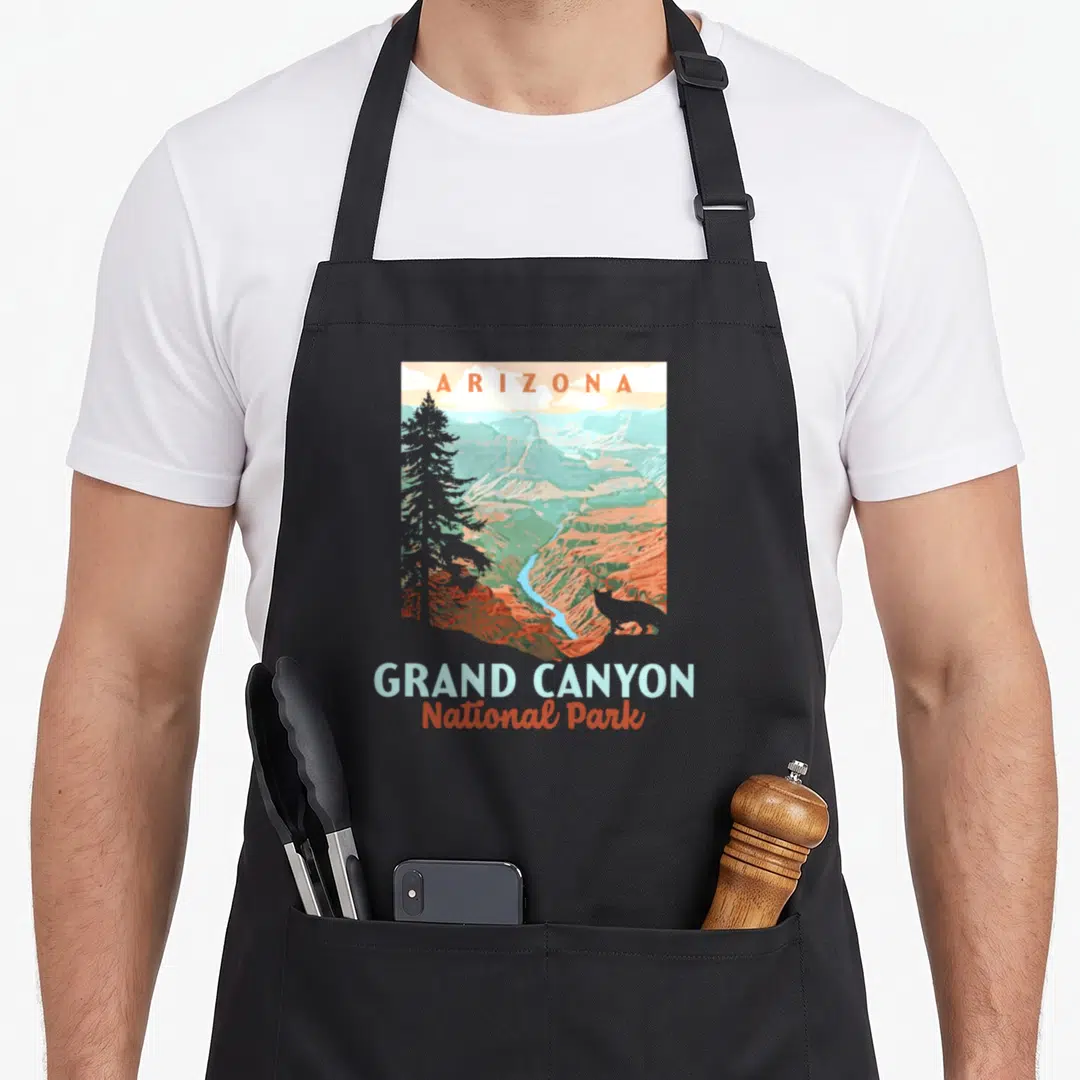 Wpa canyon apron - Retro Grand Canyon illustration with ARIZONA text and layered orange blue teal canyon landscape — shown on a black cotton canvas apron against a white background